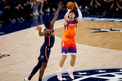 NBA常规赛现场，球员在三分线外出手投篮，防守球员起跳封盖